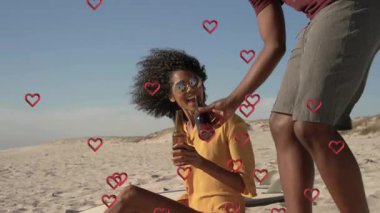 Seyahat eden çiftler aşklarını, şişeleri kadeh kaldırarak paylaşırlar. Kalpleri yüzen içki ikram ederler. Kumsal, romantizm, çift, boş zaman, açık hava, neşeli, gün batımı