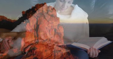 Kadın kitap boyunca süzülerek süzülüyor. Saydam dağların altında sayfaları çeviriyor. Öğrenmek için. Edebiyat, rahatlama, konforlu, doğa, tefekkür, ev, sinema