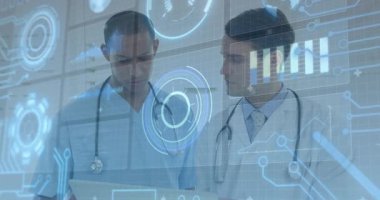 Doctor in scrubs holding tablet and projecting hologram in clinic, white coat colleague leaning in. Medical, healthcare, technology, collaboration, diagnostics, innovation, professionalism