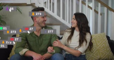 Kanepede kahkaha atan ve sosyal medya simgelerini ateşleyen çift artan nişanı gösteriyor. Romantik, samimi, hareketli, dijital, iletişim, bağlantı, eğlence