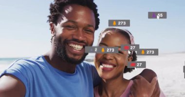 Sahilde canlı sosyal medya yayınına ev sahipliği yapan çift, izleyici sayısı artıyor, simgeler yüzüyor ve geri çekiliyor. Plaj, tatil, bağlantı, neşe, etkileşim, dijital, rahatlama