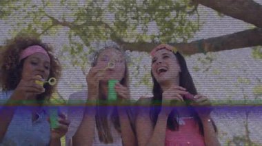 Arkadaşlar baloncukları çözeltiye daldırıyor ve pazarlama için ağaç tepe örtüsünün altına sabun köpükleri üflüyorlar. Neşe, rahatlama, açık hava, neşeli, enerjik, boş zaman, doğal