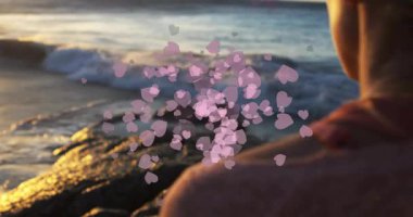 Gün batımı ışığı pembe kalplerin kümelenmesine neden oluyor, pazarlama için denize bakan bir kadının etrafına yayılıyor. Romantik, dinginlik, ruh hali, sembolizm, sanatçılık, doğa, tefekkür