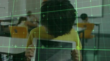 Çocuk tableti kaldırıyor ve yeşil ızgara taraması yaparken gülümsüyor. Sınıftaki cihazın kenarlarını tarıyor. Dijital, eğitim, modern, teknoloji, gençlik, sınıf, yenilik