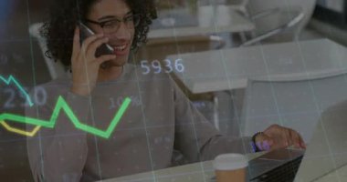 Akıllı telefonu kulağına dayayan ve dizüstü bilgisayarda yeşil-sarı market grafiklerini izleyen bir adam. Teknoloji, finans, veri, analiz, modern, çalışma alanı, iletişim