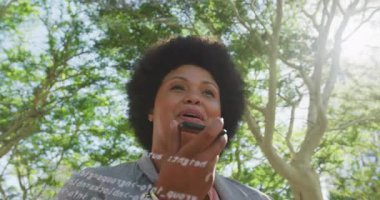 Şehir parkında telefonu kaldıran teknisyen kadın transkripsiyon kodlarıyla ses komutunu başlatıyor. Kentsel, teknoloji, açık hava, modern, yenilik, iletişim, profesyonel