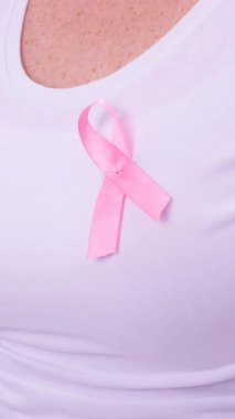 Beyaz kadın, pembe kanser farkındalığı kurdelesi takıyor ve siyah arka planda. Göğüs kanseri pozitif farkındalık kampanyası konsepti.