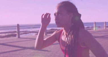 Fitness kadını gün doğumunda deniz kenarında koşuyor. Koşmaya başlamadan önce gözleri parlaklıktan koruyor. Atletik, açık hava, canlı, sağIık, aktif giyim, çevre, macera