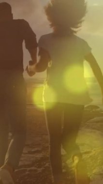 Plajda koşan bir çiftin üzerindeki ışık noktalarının canlandırması. Yaşam tarzı ve doğa konsepti dijital olarak oluşturulmuş video.