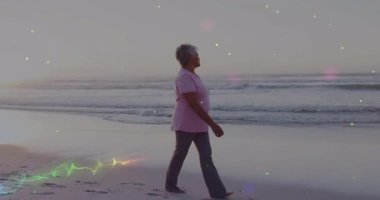 Kıdemli bir kadın ıslak kuma basıyor ve kıyı boyunca neon parıltılarıyla sağlıklı bir şekilde yürüyor. Sunbae, kumsal, kum, neon, ışık, iz, sükunet