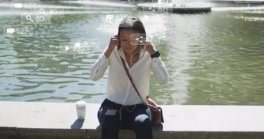 Akıllı telefon yerleştiren ve kulaklıkları takan bir kadın sosyal medya simgelerinin çeşmenin yanında yükselmesine neden oluyor. Mobil, modern, parlak, teknoloji, kentsel, dingin, canlı