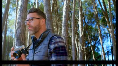 Çam ormanında objektifi ayarlayan olgun fotoğrafçı çekim yapmadan önce titreşimli odak çemberleri gösteriyor. Doğa, keşif, nostalji, açık hava, sükunet, sanatçılık, klasik