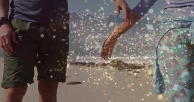 Romantik çift kumsalda el uzatıyorlar, altın parçacıkları ateşliyorlar birliğin havasını oluşturuyorlar. Romantizm, bağlantı, dinginlik, cazibe, şafak, ahenk, yakınlık