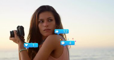 Sosyal medya yaratıcısı kamera kıyılarını yükseltiyor, yükselen mavi baloncuklar gün batımını yakalıyor. Eğilim, nüfuz, dinginlik, kıyı, farkındalık, resim, teknoloji