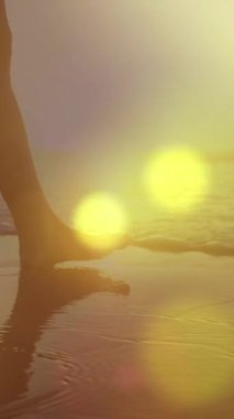 Sahilde yürüyen bir kadının orta kısmına karşı parlak sarı ışık lekeleri. Aşk ve ilişki kavramı