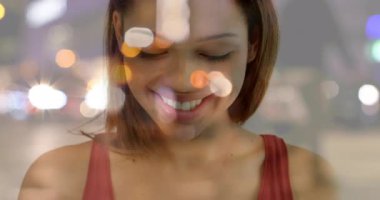 Fotoğrafta gülümseyen, kırmızı bluzlu, elinde fotoğraf makinesi olan bir kadın var. Bokeh ışıklarının arasında. Portre, cazibe, romantik, nostaljik, sanatsal, parıltılı, zarif