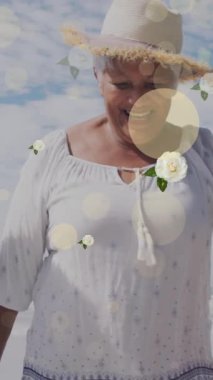 Sahildeki mutlu Afrikalı Amerikalı büyükanne ve torunlar üzerinde benekler ve çiçeklerin animasyonu. Çocukluk, eğlence, aile ve tatil konsepti dijital olarak oluşturulmuş video.