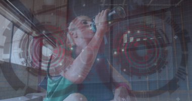 Yeşil kolsuz tişörtlü kadın spor salonunda HUD grafikli su şişesinden su içiyor. Fitness, technology, wellness, activewear, sports, motivasyon, health