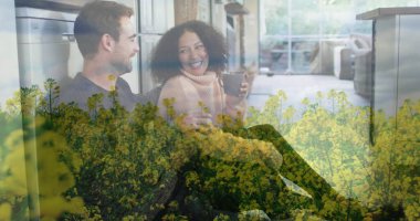 Holding mugs couple wearing sweater and shirt leaning against home kitchen island with sliding door. Cozy, domestic, contemporary, lifestyle, relaxation, minimalism, harmony