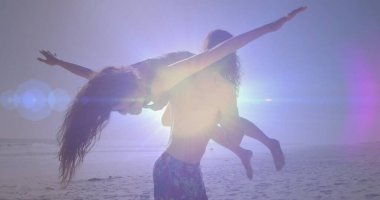 Fit adam, kadın partneri kumlu sahil boyunca şort ve bikiniyle kaldırıyor. Macera, romantizm, canlılık, açık hava, coşku, rahatlık, kıyı