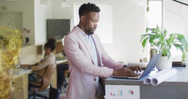 Orta yaşlı erkek, bilgisayarın etrafında dönen altın parçacıkları yaratarak teknolojik veri kavrayışlarını sağlıyor. Teknoloji, yenilik, üretkenlik, enerji, yaratıcılık, işbirliği, modern