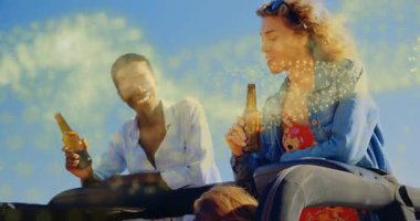 İki kadın ellerinde bira ile bagaj kapısına tünemiş içecek reklamı için altın efekt yapmaya başlıyorlar. Kutlama, dostluk, eğlence, açık hava, canlı, spontane, yaşam tarzı