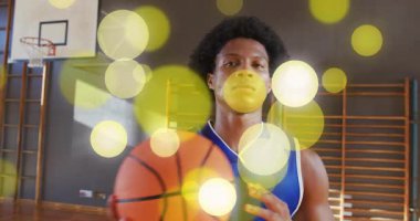 Basketbolcu topu yukarı fırlatıyor. Bahşiş kutusu kontrolünde dönüyor. Sahada sarı bokeh var. Spor, atlet, antrenman, hareket, odaklanma, dayanıklılık, performans