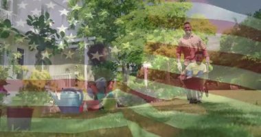 Çocuğun el arabasına tırmanması, babanın evde bahçıvanlık yaparken annesine doğru itmesine neden oluyor. Aile, açık hava, doğa, ebeveynlik, bağlılık, boş zaman, bahçıvanlık