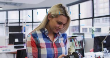 Teknoloji ofisindeki kamera ayarlarını inceleyen bir kadın kafasının etrafında dönen animasyon şekilleri başlatıyor. Yaratıcı, teknoloji, modern, odaklanma, ifade, yenilik, çalışma alanı