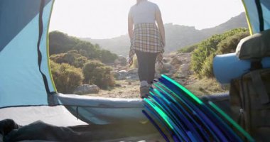 Çadır kadın yürüyüşçüden inerek tepelere doğru yürüyor neon çizgileriyle dönüyor, geri çekiliyor. Macera, keşif, vahşi doğa, açık hava, manzara, işlevsellik, dinamik