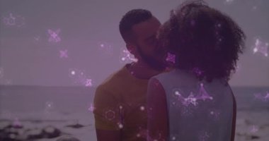 Kadının yüzünü kavrayan ve AR teknolojisini kullanarak mor molekülleri taşıyan bir adam kıyıda öpüşmeye başlıyor. Romantik, samimiyet, aşk, bağlantı, dinginlik, soyut, dijital