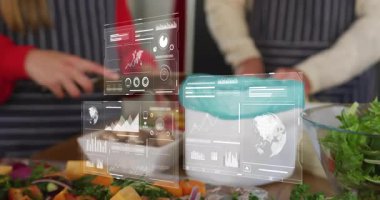 İki aşçı salatayı dilimliyor holografik çizelgeleri güncelliyor, limon suyu ekliyor ve besinleri ölçüyorlar. Aşçılık, teknoloji, mutfak, işbirliği, yenilik, modern, sağlık