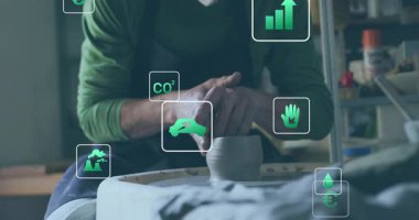 Potter ellerini ıslatıyor ve seramik üzerinde kilin merkezini oluşturuyor, yeşil simgelerle çevreci gemileri şekillendiriyor. Sanatçılık, sürdürülebilirlik, çevre dostu, el yapımı, sanatsal, teknik, çevresel