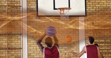 Erkek sporcular mor ve turuncu topları getiriyorlar ve serbest atış antrenmanı için jimnastik çemberinin altına atıyorlar. Eğitim, takım çalışması, rekabetçi, motivasyon, spor, şehir, eylem