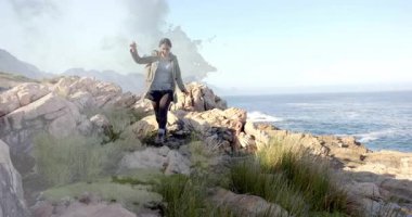 Ufukta beliren kadın yürüyüşçü, kıyı şeridini keşfederken sırt çantasını indiriyor ve ayarlıyor. Macera, keşif, engebeli, manzaralı, kararlılık, özgürlük, yaban hayat