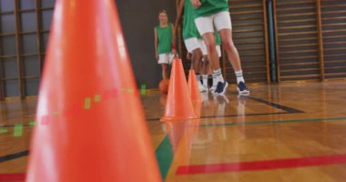 İlk oyuncu öne çıkıyor ve neon külahlar ayak hareketlerine rehberlik ederken top sürme talimini başlatıyor. Eğitim, çeviklik, koordinasyon, atletizm, takım, beceri, uygulama