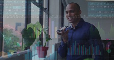 Speaking businessman using smartphone by office window, with plants, charts, graphs, copy space. Professional, urban, modern, technology, data analysis, productivity, environment