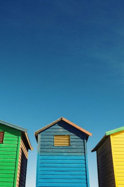 Güneşli bir günde gökyüzüne karşı rengarenk plaj kulübesinin alçak açılı görüntüsü
