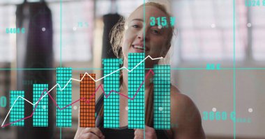 Siyah bluz giyen, spor salonunda boks eldiveni takan, kum torbaları, pencereleri ve kaplamalarıyla gülümseyen bir kadın. Fitness, power, yetkilendirme, kararlılık, sağlık, eğitim, modern