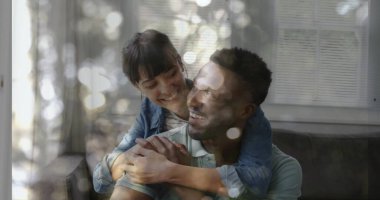 Embracing couple hugging on sofa in living room, with window blinds reflections and soft cushions. Romantic, intimacy, comfort, cozy, interior, illumination, affection