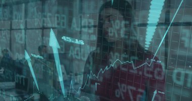 Analyzing woman in burgundy blouse examining rising graph on digital screen in office, with laptops. Technology, data, innovation, collaboration, modern, productivity, business