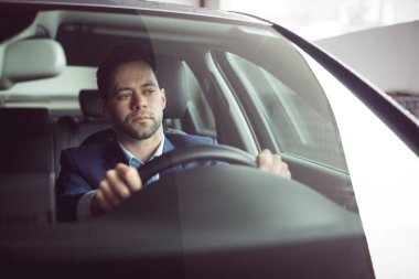 Man is sitting behind steering wheel inside flat design sedan interior with leather seats. Vehicle, professionalism, interior design, urban environment, focus, sleek, concentration