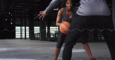 Basketbol topuna vuran, bacaklarının altından spor talimi yapan bir kadın defans oyuncusu. Kentsel, atletik, aksiyon, eğitim, hareket, çağdaş, canlı