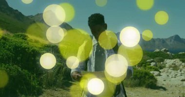 Sırt çantalı gezgin kıyı şeridinde harita açıyor ve rota çizerken hareketli sarı dairelere neden oluyor. Macera, keşif, seyrüsefer, manzara, vahşi doğa, açık hava, keşif