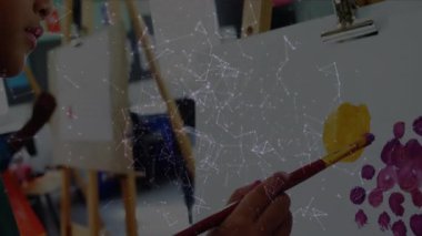 Fırçayı sarı boyaya batıran kız mor noktalı çemberler oluşturuyor ve öğrencileri açığa çıkarıyor. Çocuklar, sanat, yaratıcılık, sınıf, sanatsal, öğrenme, renkli