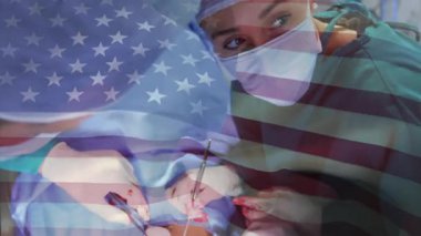 ABD bayrağı beliriyor, baş cerrah forseps hizalıyor ve ameliyat sırasında makas kullanıyor. Tıbbi, sağlık, işletme, profesyonellik, kesinlik, takım çalışması, kısır