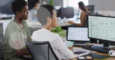 Kıvırcık saçlı işçi yeşil gömlekli partnere iş planı tartışmasında rehberlik ediyor. İşbirliği, takım çalışması, ofis, üretkenlik, tasarım, dijital, iletişim