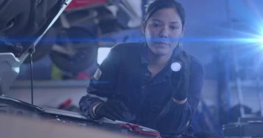 Garajda kaputa dayanmış el feneri tutan tamirci pil kablosu tarıyor ve klempi sıkılaştırıyor. Otomobil tamiri, teknisyen, endüstriyel, sorun giderici, endüstriyel tasarım, tamirat, araç bakımı