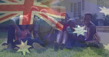 Aile çimlerde oturuyor, pazarlamacı pazarlama için yarı şeffaf Avustralya bayrağı örtüyor. Aile, açık hava, topluluk, çok kültürlü, kutlama, uyum, neşe