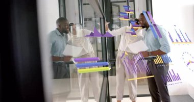 İş arkadaşları baskıları inceliyor ve iş analizi için canlı bar ve çizgi çizelgelerini not ediyor. İşbirliği, analitik, yenilik, grafik, takım çalışması, veri görselleştirme, profesyonel